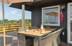 uma mesa de madeira num deque com cadeiras e um guarda-sol em Stunning Home In Knebel With House Sea View em Ørby