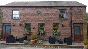 a brick building with black chairs in front of it at Fern Farm Cottages in Buxton