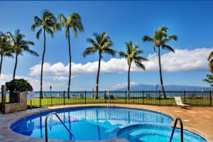 a swimming pool with palm trees and the ocean at Paki Maui 326 in Kahana