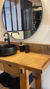 ein Bad mit einem Waschbecken und einem Spiegel in der Unterkunft Maison avec JACUZZI Privatif, L'Antre 2, WIFI,TV,CLIM in Bessan