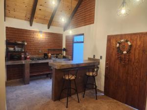 a kitchen with a bar with stools and a brick wall at Villa Onawa by Natut Huasca in Huasca de Ocampo
