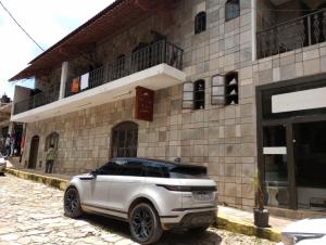 a white suv parked in front of a building at Pousada Maciel in São Thomé das Letras