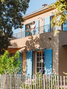 two people on the balcony of a house with blue shutters at Residence CASE DI PI GNA, deux magnifiques villas indépendantes avec piscines individuelles , proches de la plage d'Algajola in Algajola