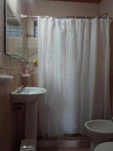 Un baño con una cortina de ducha blanca y un lavabo. en Luna Plateada - Terrafirme, en Villa Yacanto