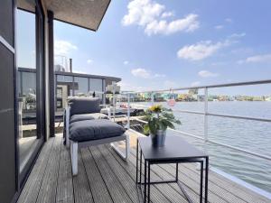 un balcón con una silla y una mesa en un barco en Jopies Houseboat, en Maasbommel