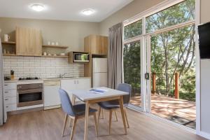 eine Küche mit einem Tisch und Stühlen sowie einem großen Fenster in der Unterkunft Ramada Resort by Wyndham Phillip Island in Cowes