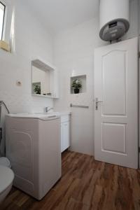 a white bathroom with a sink and a door at Apartments with a parking space Povljana, Pag - 11516 in Povljana