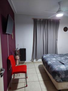 - une chambre avec un lit et une chaise rouge dans l'établissement Departamento Viamonte con cochera, à Bahía Blanca