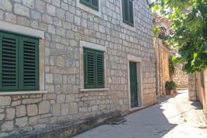 拉斯托伏Apartments and rooms with WiFi Lastovo - 13678的一座石头建筑,设有绿色的窗户和街道