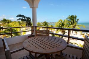 a wooden table on a balcony with a view of the beach at Sandy Feet Beach Resort in Placencia