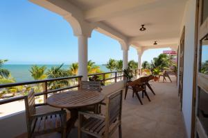 balcone con tavolo, sedie e vista sull'oceano di Sandy Feet Beach Resort a Placencia