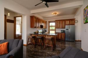 a kitchen with wooden cabinets and a kitchen island with bar stools at Sandy Feet Beach Resort in Placencia