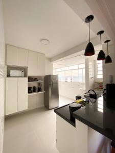 uma cozinha com armários brancos e um frigorífico de aço inoxidável em Apartamento em Belo Horizonte em Belo Horizonte