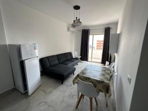 uma sala de estar com um sofá, uma mesa e um frigorífico em Beach front Durres 2 em Durrës