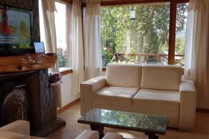 sala de estar con sofá blanco y chimenea en Casa de montaña con vistas al lago y a los cerros en Villa La Angostura