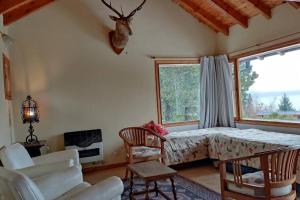 sala de estar con cama y ventana en Casa de montaña con vistas al lago y a los cerros en Villa La Angostura