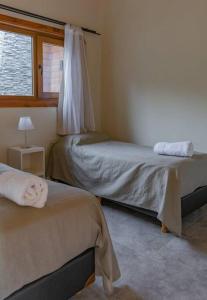 a bedroom with two beds and a window at Casa de montaña con vistas al lago y a los cerros in Villa La Angostura