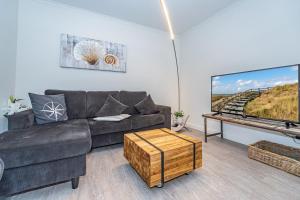 een woonkamer met een bank en een grote tv bij Meersalz in Westerland