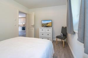een slaapkamer met een wit bed en een televisie bij Meersalz in Westerland