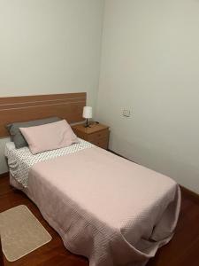 a bedroom with a bed and a table with a lamp at Piso pineda in Monforte de Lemos