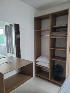 a room with a bed and a desk and shelves at Glamour Meia Praia in Itapema