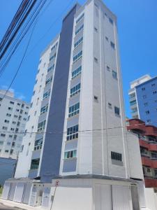 a tall white building on a street with buildings at Glamour Meia Praia in Itapema