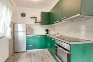 a kitchen with green cabinets and a white refrigerator at Holiday house with a parking space Fuzine, Gorski kotar - 20518 in Lokve