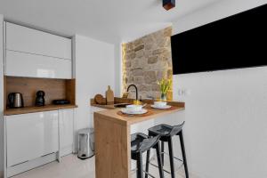 a kitchen with a counter with stools and a sink at Apartments by the sea Makarska - 21443 in Makarska +12 photos