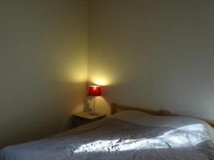 a bedroom with a bed and a red lamp at Charmante Ferme Rénovée avec Terrasse à 7 km du Mans, 8 Couchages, TV, Internet, Cuisine Équipée - FR-1-410-254 in La Bazoge