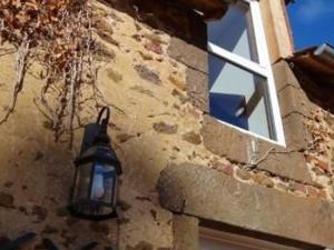 a light on the side of a building with a window at Charmante Ferme Rénovée avec Terrasse à 7 km du Mans, 8 Couchages, TV, Internet, Cuisine Équipée - FR-1-410-254 in La Bazoge