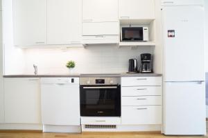uma cozinha branca com armários e electrodomésticos brancos em Railway station & Central studio em Oulu