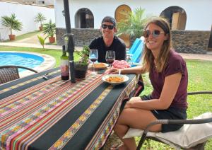 a man and a woman sitting at a table with food and wine at Montemar Apart Hotel - Playa Huanchaco in Huanchaco