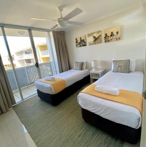 a hotel room with two beds and a balcony at Seachange Coolum Beach in Coolum Beach