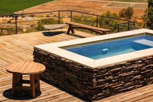 a swimming pool on a deck with a bench and a table at Villa Garven in Valle de Guadalupe