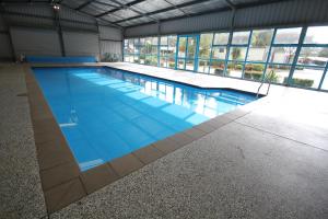 a large swimming pool with blue water in a building at Wonthaggi Park Lane Holiday Park in Wonthaggi