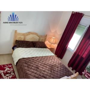 APPARTEMENT AL WAHDA في تازة: غرفة نوم بسرير ونافذة ذات ستائر حمراء