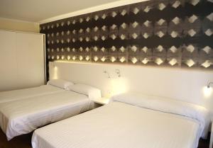 two beds in a hotel room with white sheets at Pension los Arcos in Los Arcos