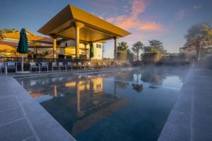 a swimming pool with chairs and a building with a building at Regal Palms Resort in Rotorua