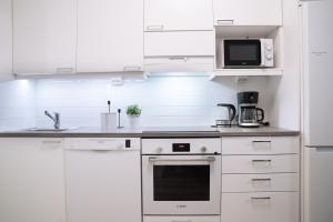 a white kitchen with a stove and a microwave at Top location IICenter IIParking in Oulu