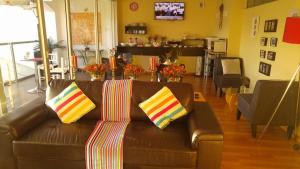 una sala de estar con un sofá de cuero marrón con almohadas coloridas en CasaHotel El Tambo Huancayo, en Huancayo
