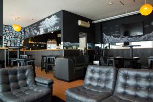 a bar with leather furniture and a bar with a counter at Hakuba Echo Hotel and Apartments in Hakuba
