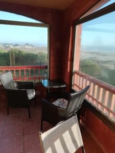 a balcony with chairs and a table and windows at Condominio Ilimay Las Cruces in Las Cruces