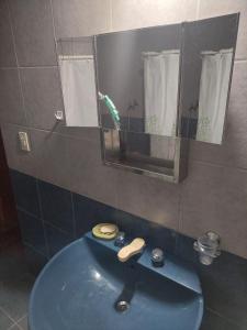y baño con lavabo azul y espejo. en Pilpilcura en Dina Huapi