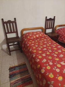 1 dormitorio con 2 sillas y 1 cama con manta roja en Pilpilcura en Dina Huapi