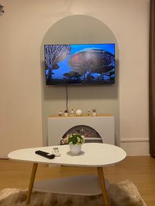 a living room with a table and a tv on the wall at PTJ Style Condotel คอนโดเมืองทอง in Ban Bang Phang