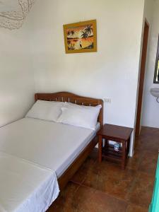 a bedroom with a bed and a side table at Jeno Tourist Inn in San Vicente