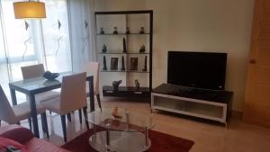 een woonkamer met een televisie en een tafel en stoelen bij Apartamento Carabuxeira 1 in Sanxenxo