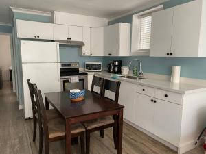 cocina con armarios blancos, mesa y sillas en jane's cozy suite en Surrey