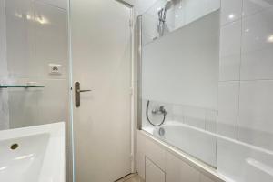 a white bathroom with a shower and a tub at Le vieux MassyRER600mOrly20 minNetflixNeuf M13 in Massy