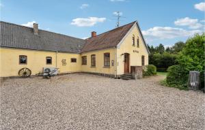 a large yellow house with a gravel driveway at Awesome Home In Stenstrup With Wifi in Stenstrup